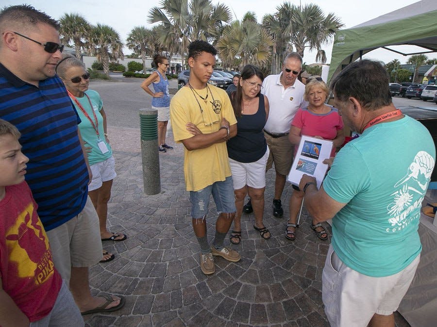 Volunteers walking through a lighting demonstration with guests before Turtle Dig